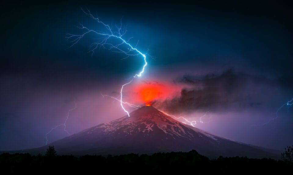 a bolt of lightning strikes over an erupting volcano at night in Chile