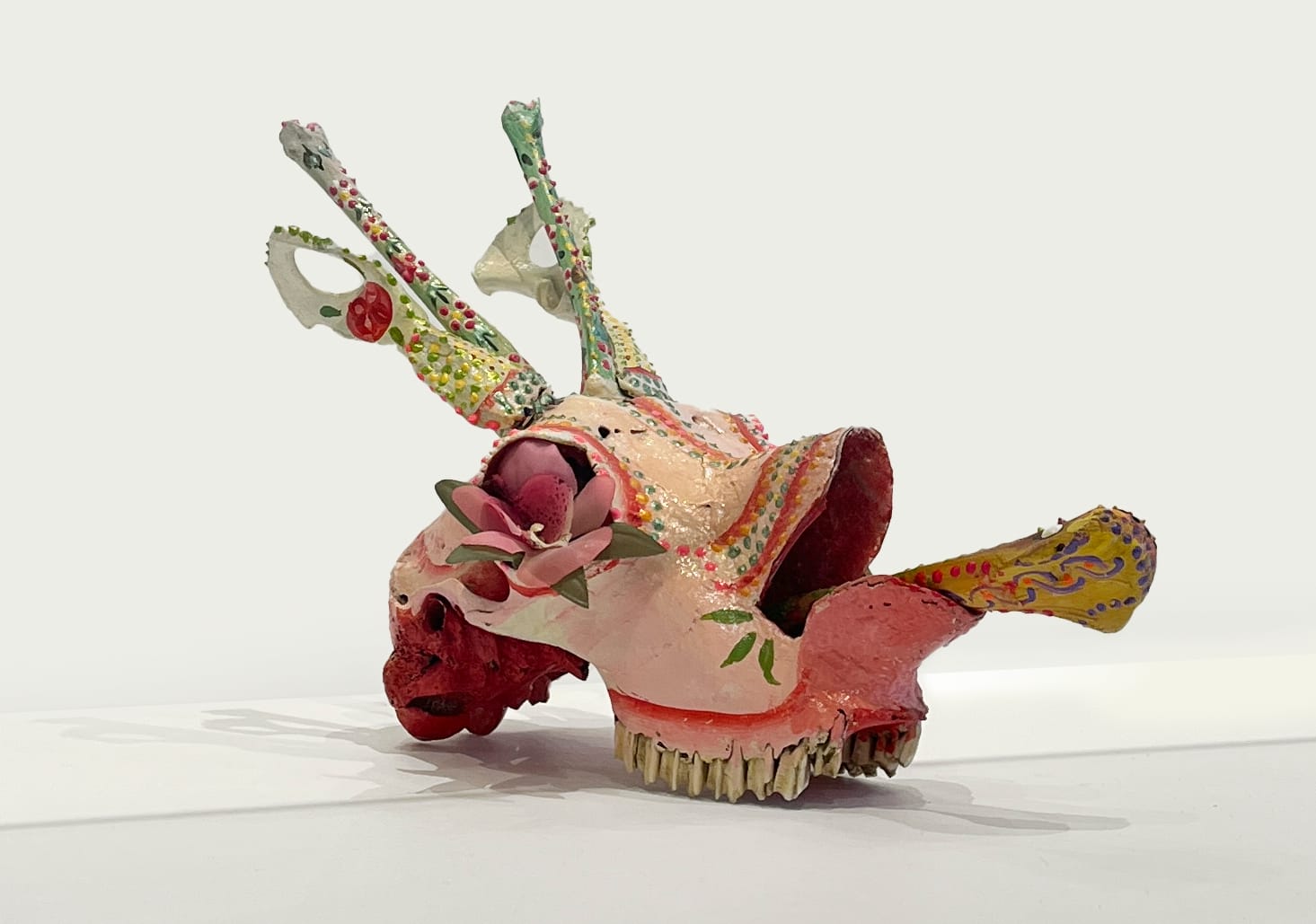 a painted pink deer skull with a snake coming from its mouth