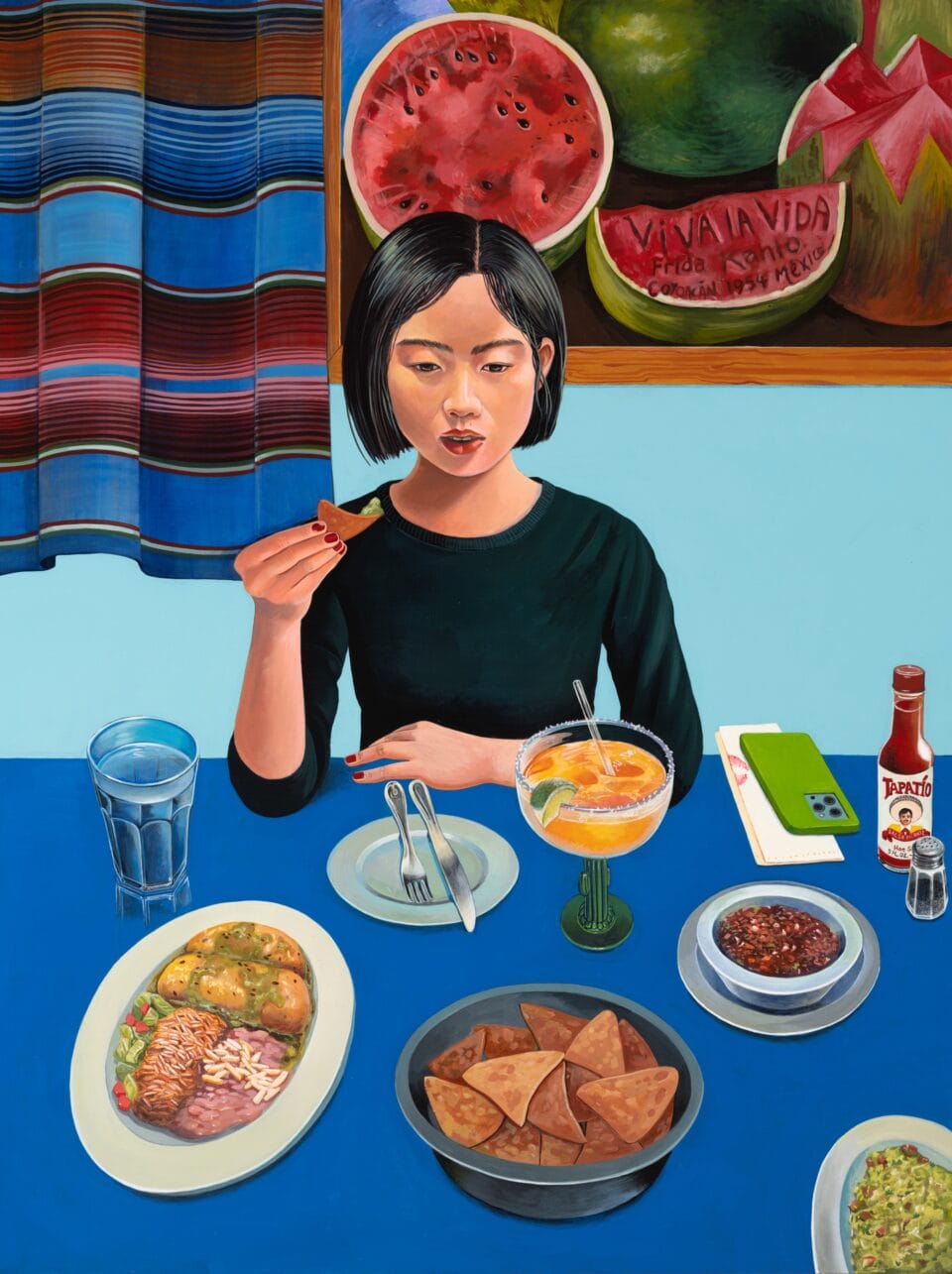 an Asian woman sits at a table with a blue tablecloth, holding food to her mouth with chopsticks, with numerous plates of food in front of her