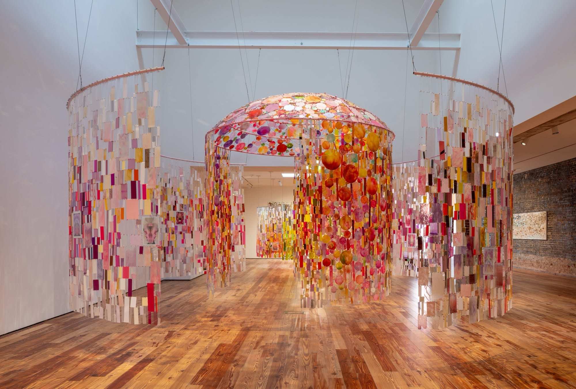 an installation view of colorful, suspended mixed-media tapestry installations
