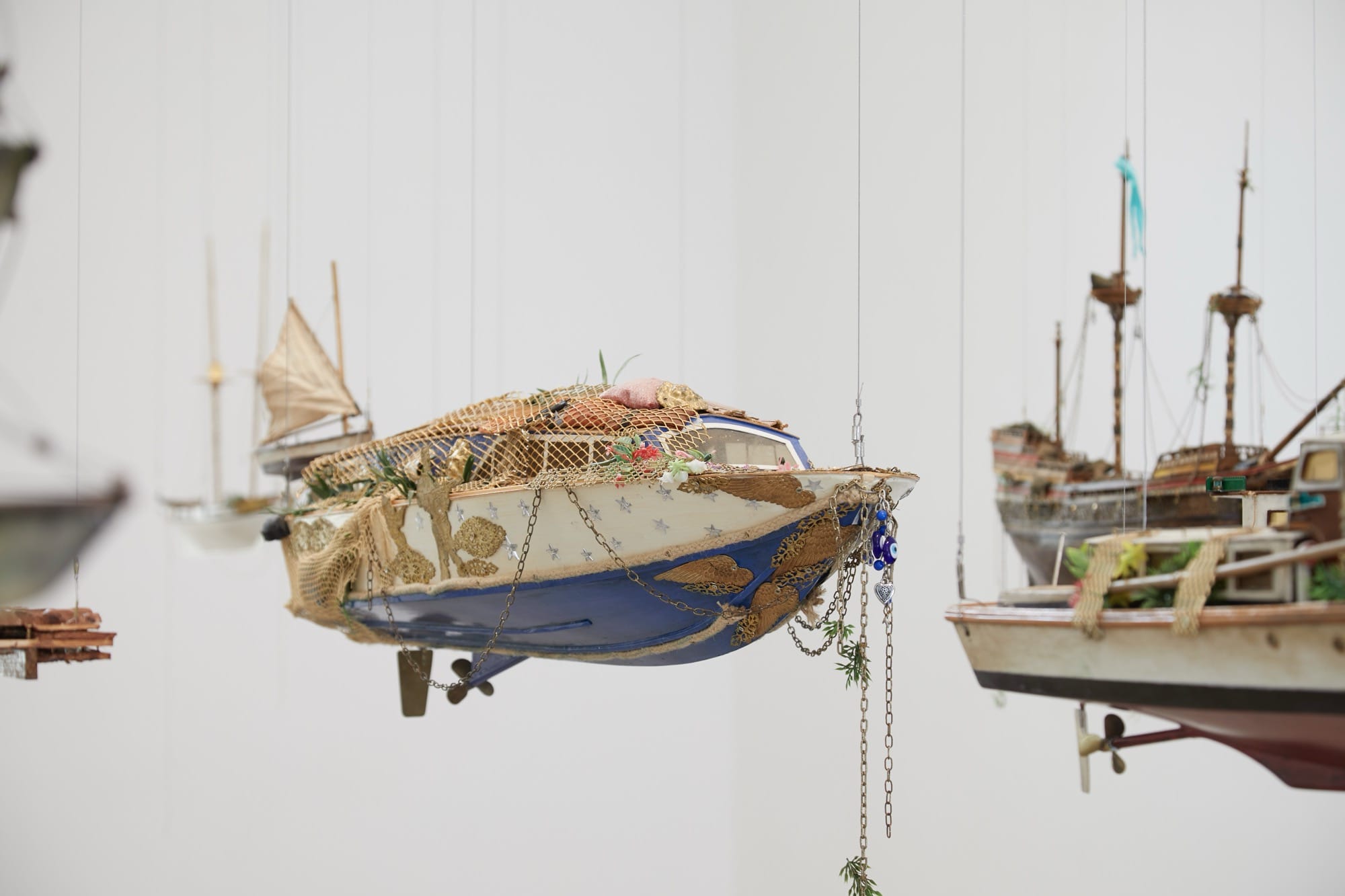 a collection of boats hangs in a gallery