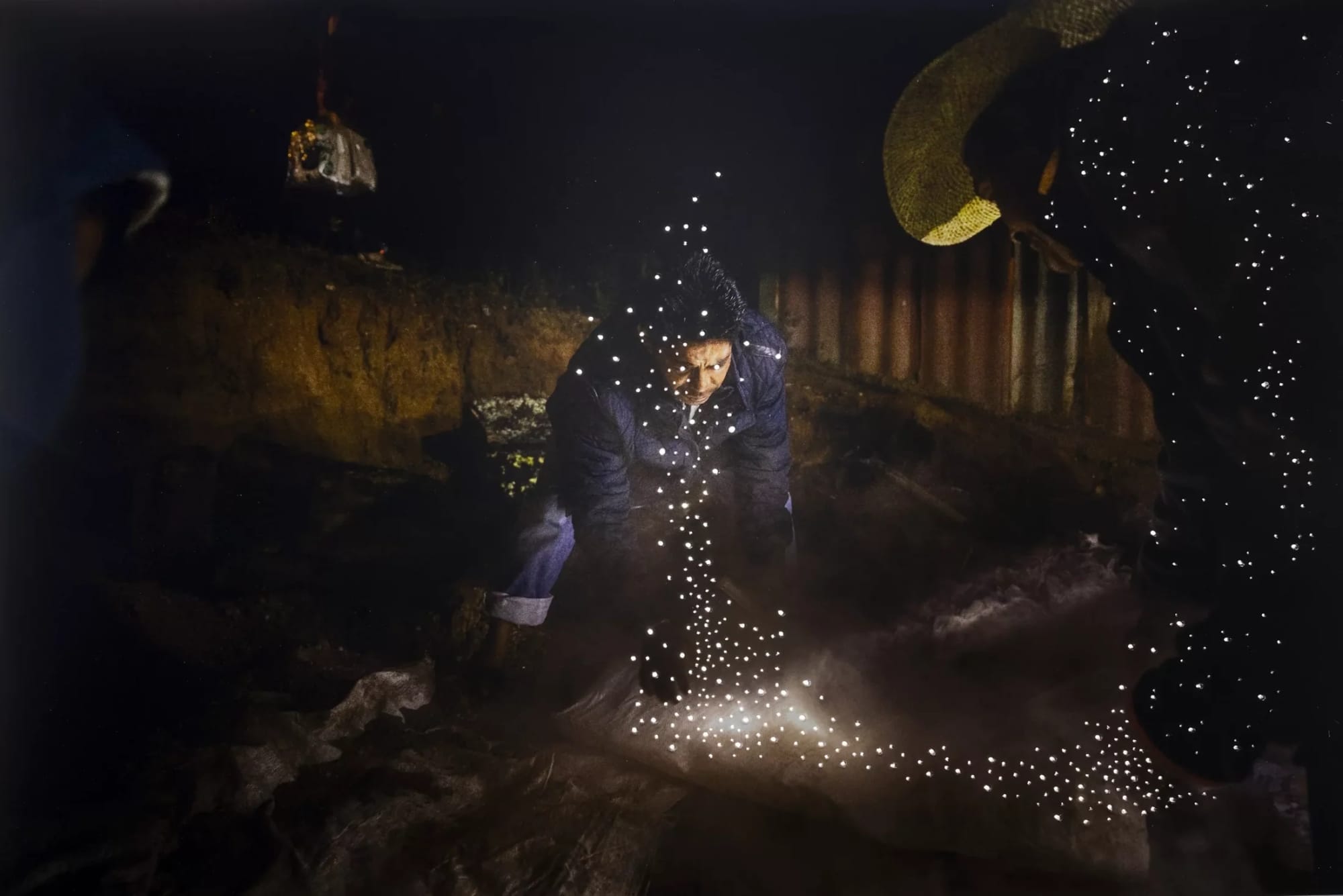 small holes pierce a dark photo of men wrapping up a body