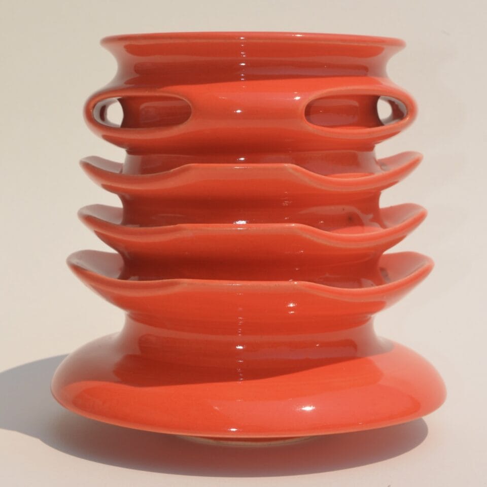 a geometric red vessel with ribbed walls