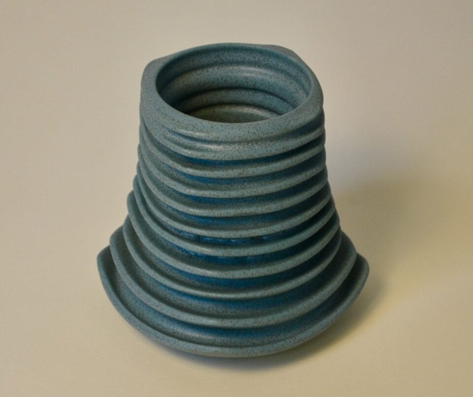 a cylindrical geometric vessels in smoky blue with ribbed walls
