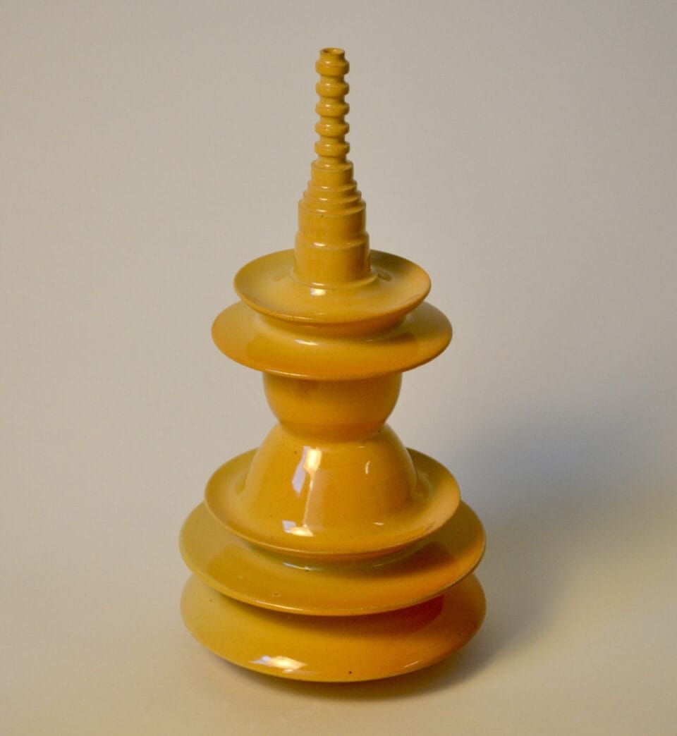 a geometric yellow sculpture with ribbed walls, stacked spheres, and concentric circle forms