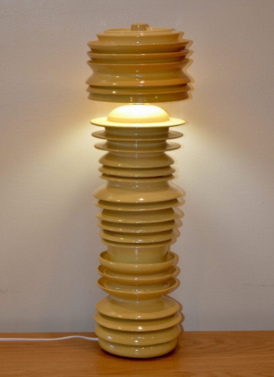 a sculptural geometric yellow standing lamp with ribbed walls and concentric circle forms
