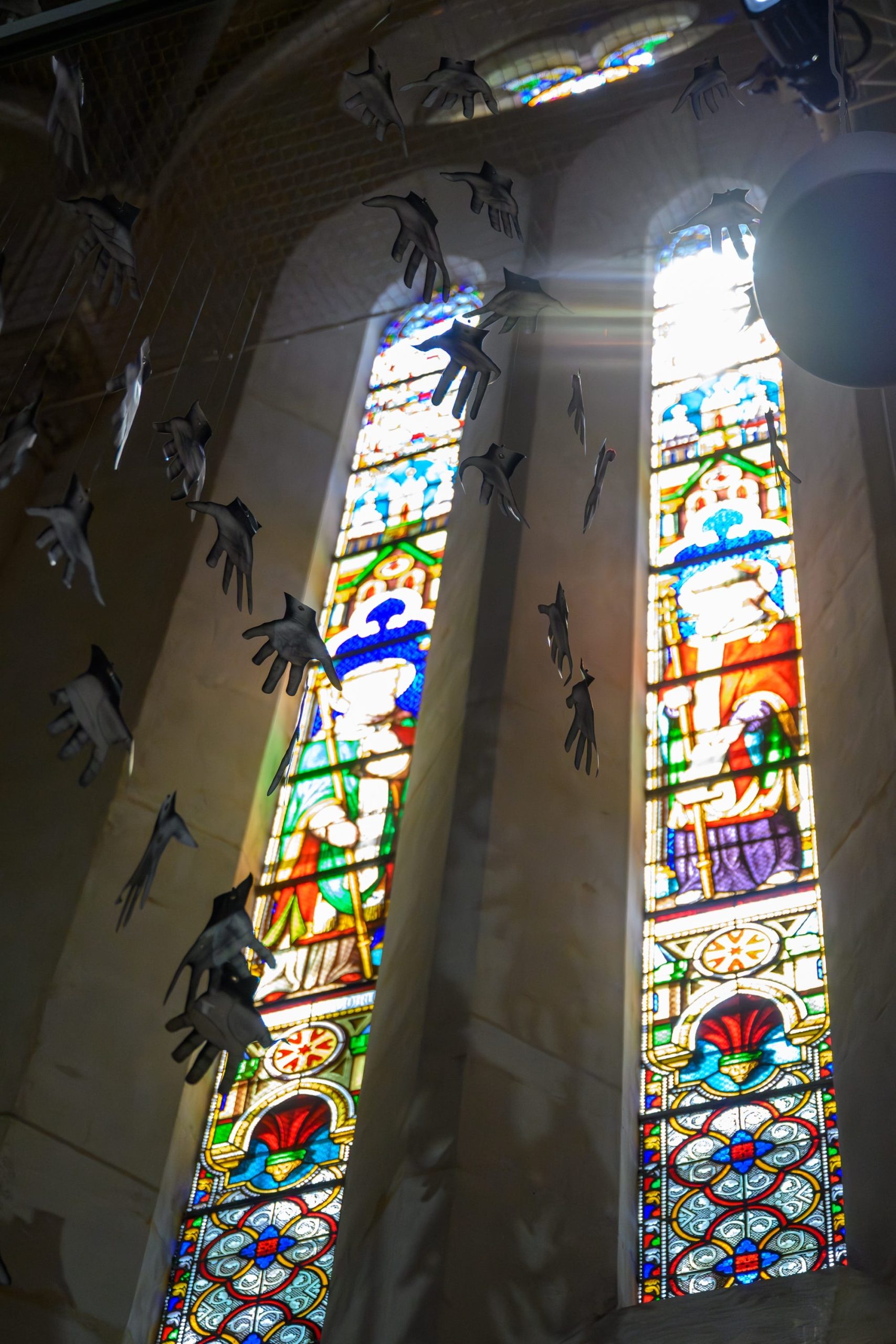 hands suspend in front of stained glass windows