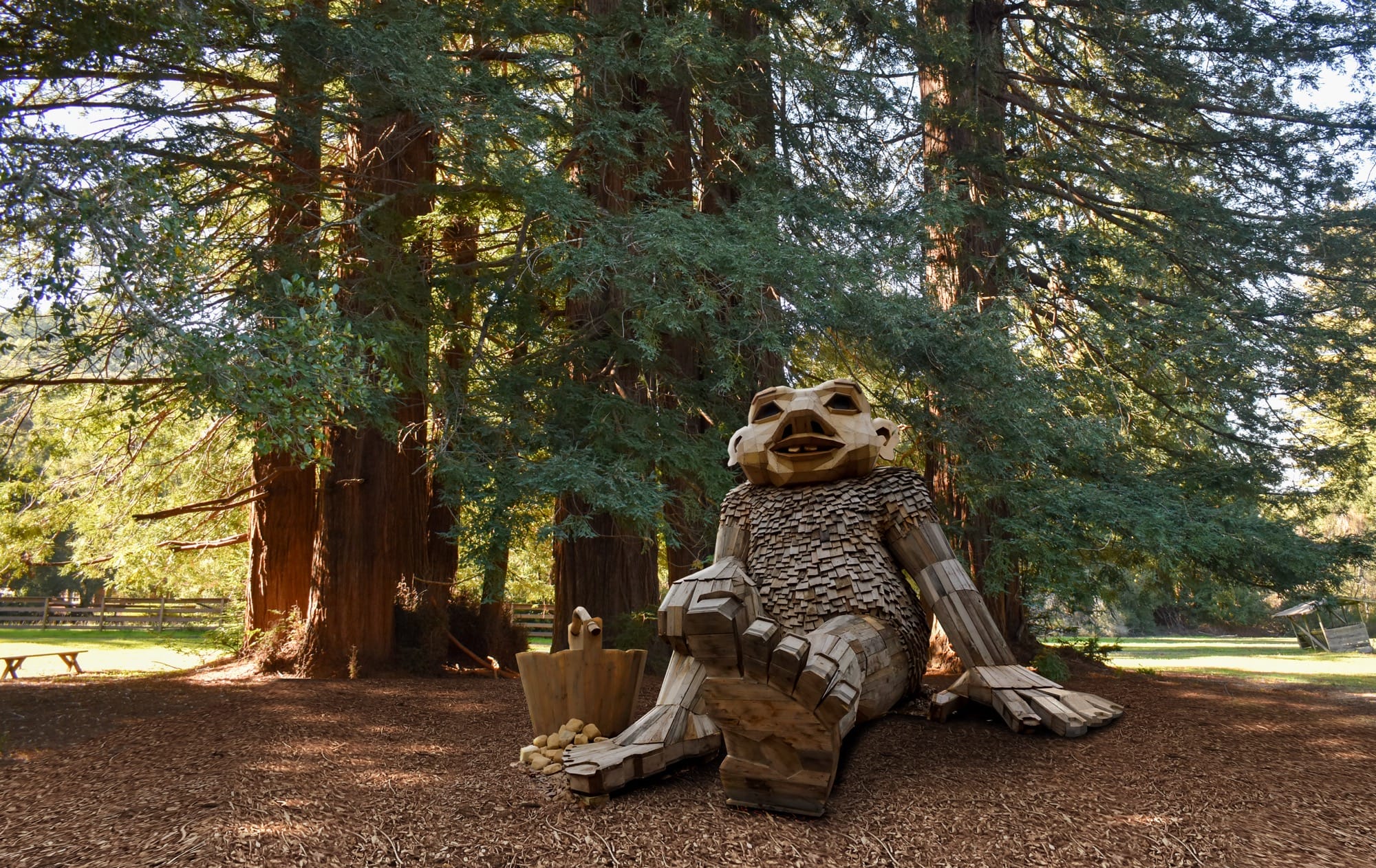 a giant wood troll seated in a woodland