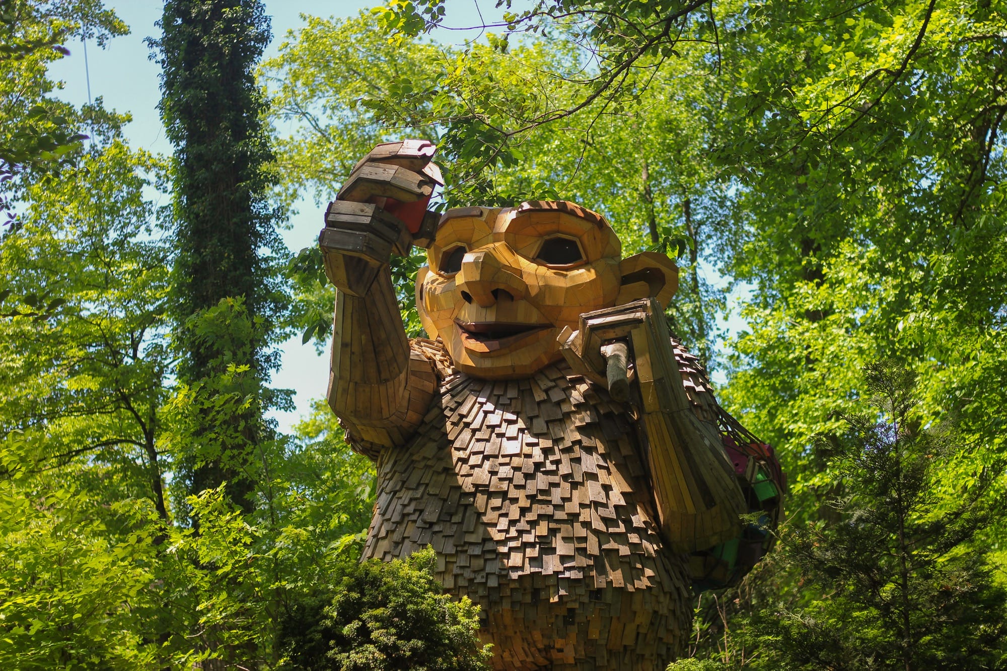 a giant wood troll placing birdhouses on trees