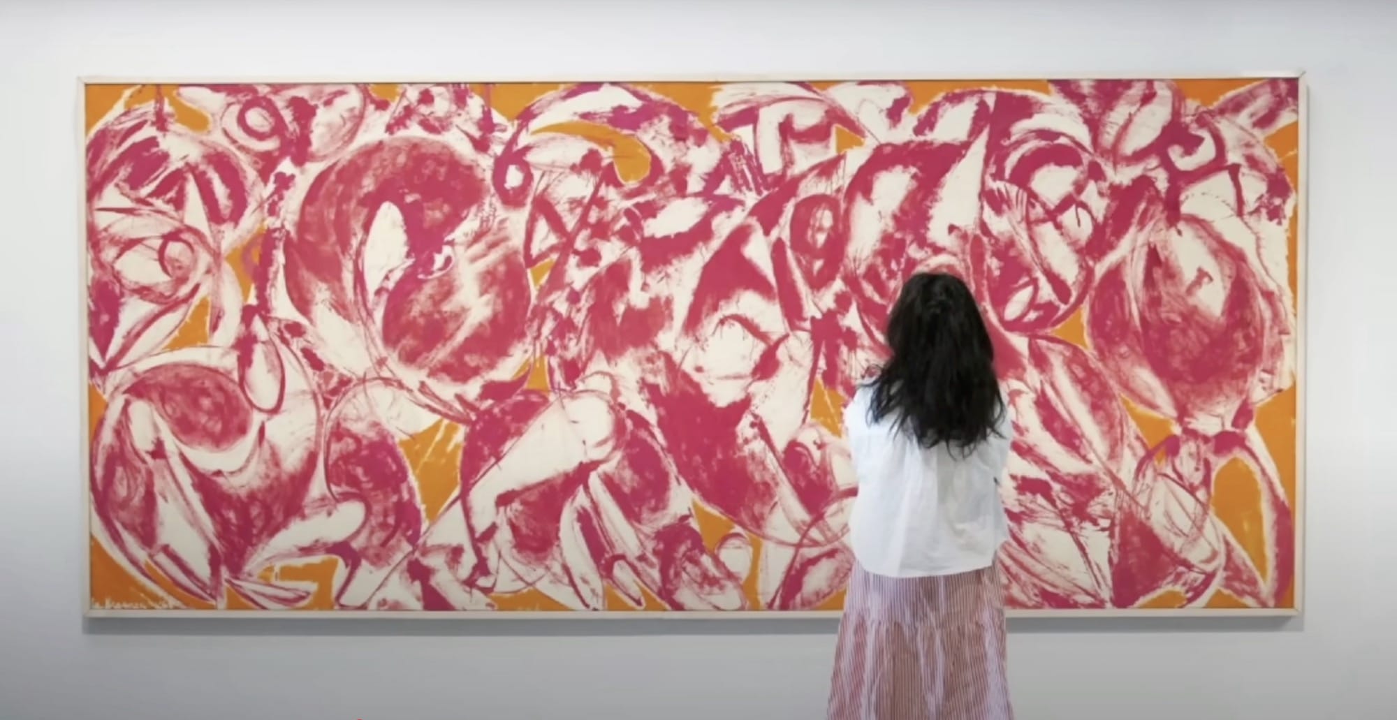 a woman looks at an abstract painting by Jackson Pollock