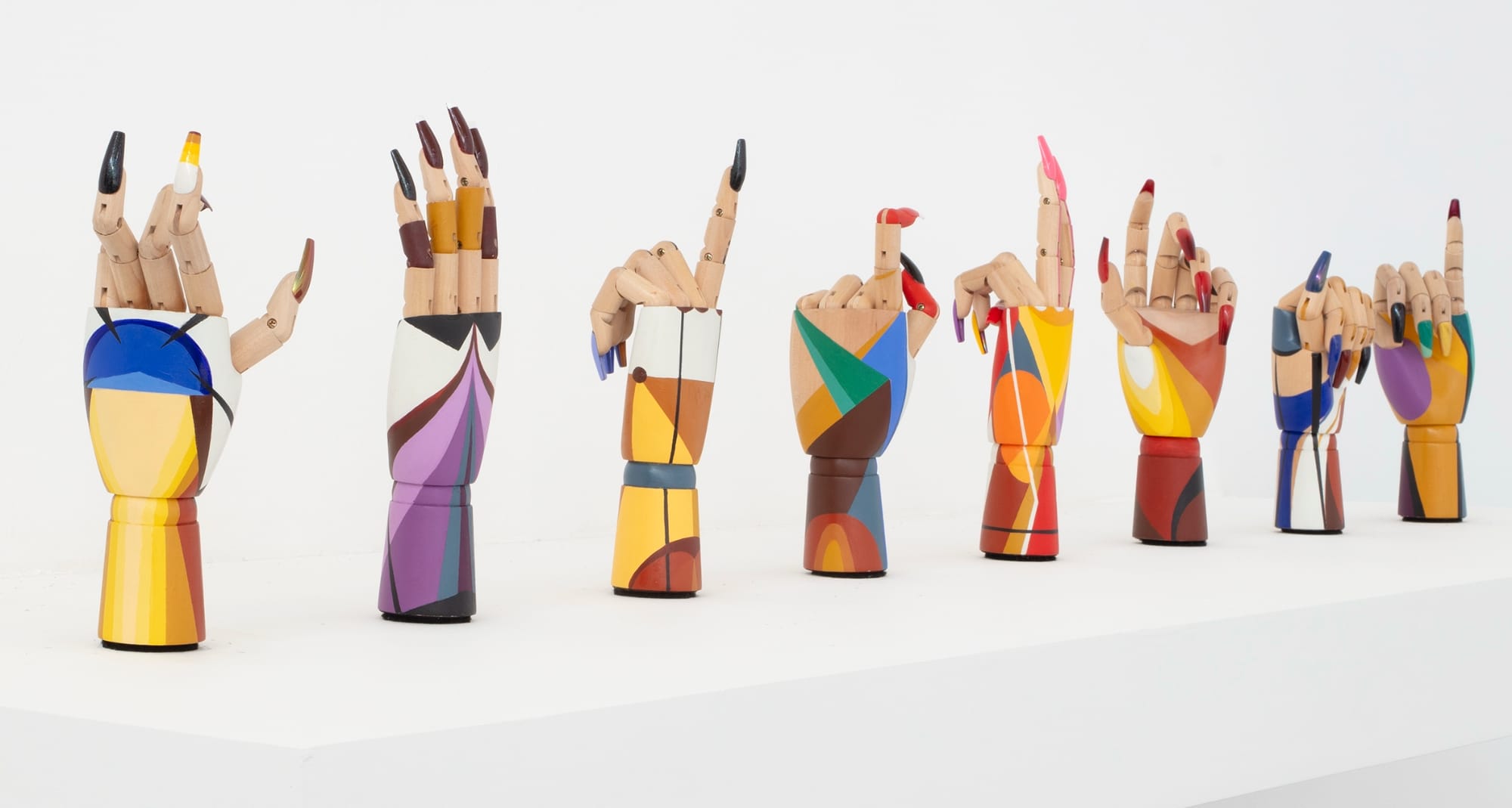 a collection of wooden hand mannequins painted with fake nails