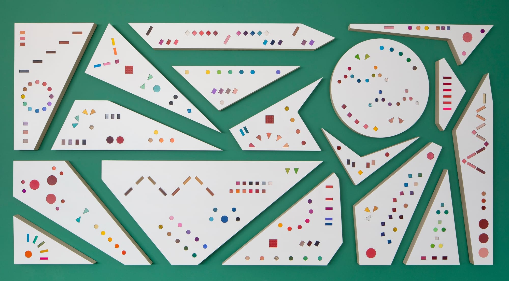 a collection of white geometric works with colorful shapes on a green background