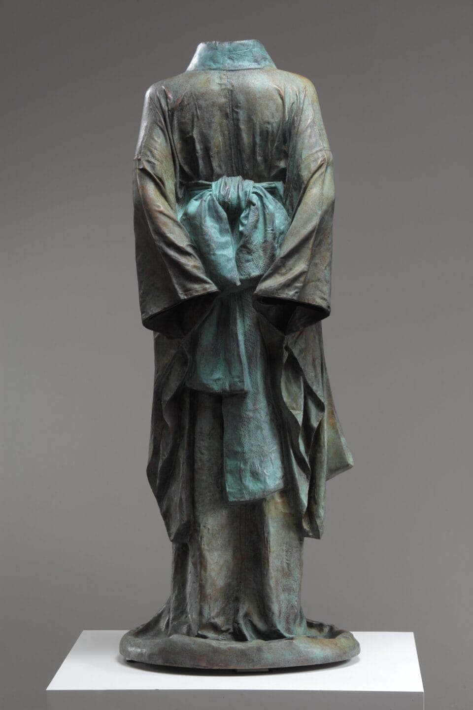 the back of a bronze sculpture of a Japanese robe or gown with a large bow in the back