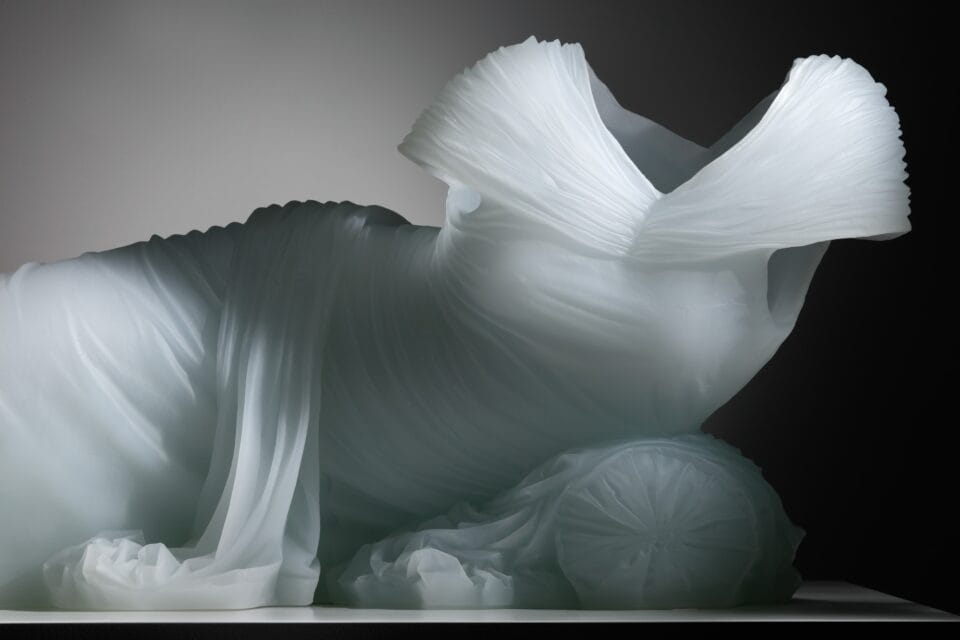 a cast glass sculpture of exaggerated drapery on a gown on a lounging figure, with no body present