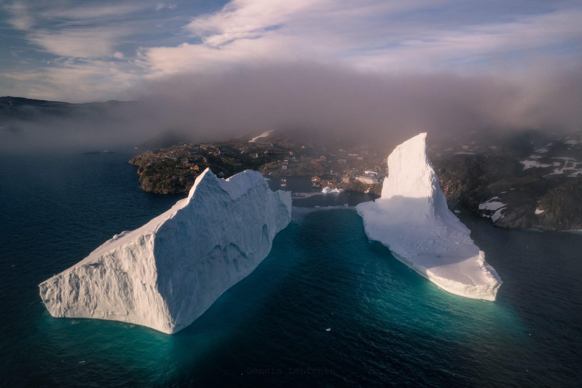 two giant icebergs seen from the air in a small town in Greenland