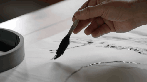 a gif of ink being painted onto a sheet of paper with a soft brush