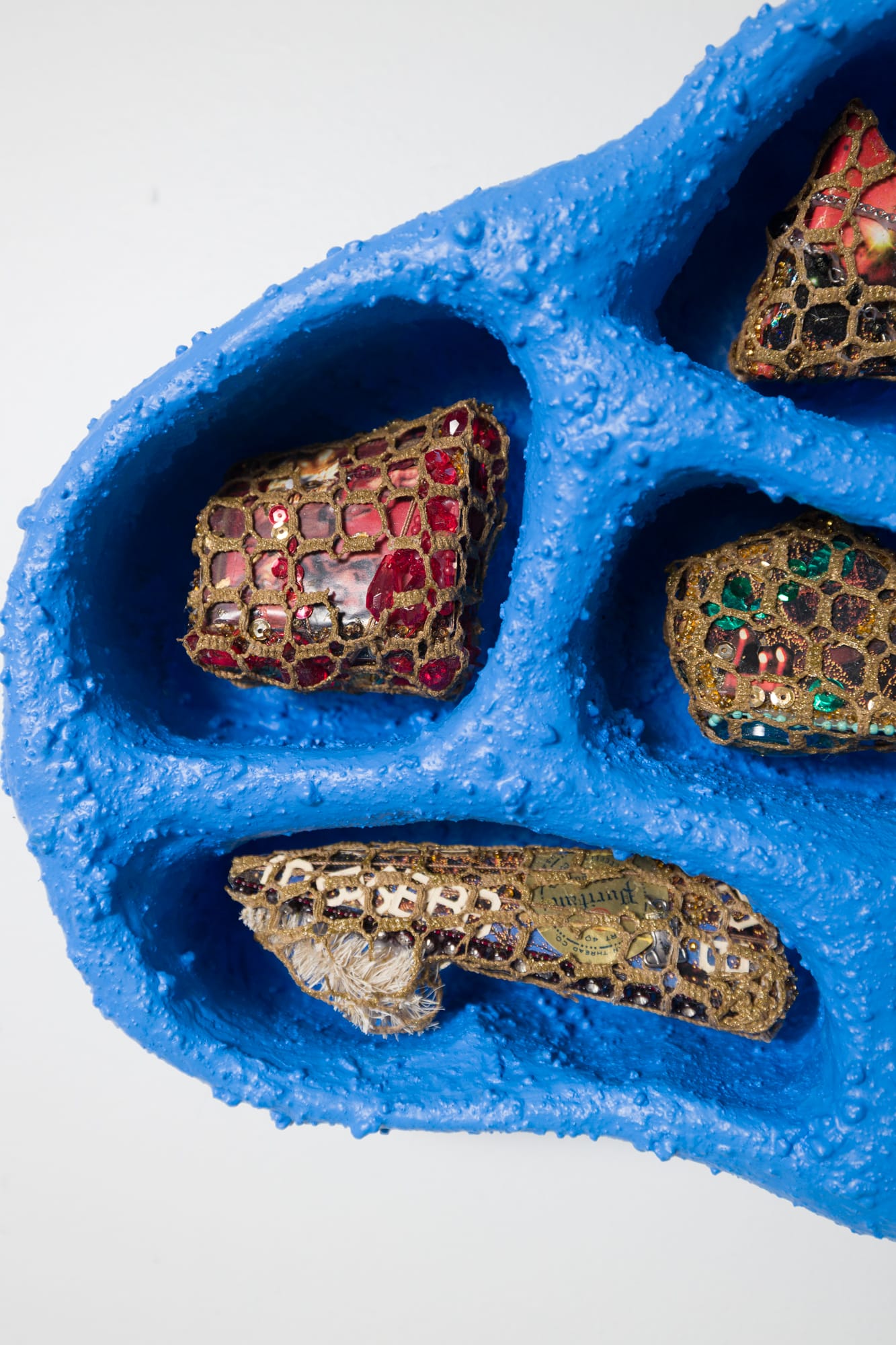 a detail of a blue cloud-like compartmented wall sculpture with niches for tiny crocheted objects