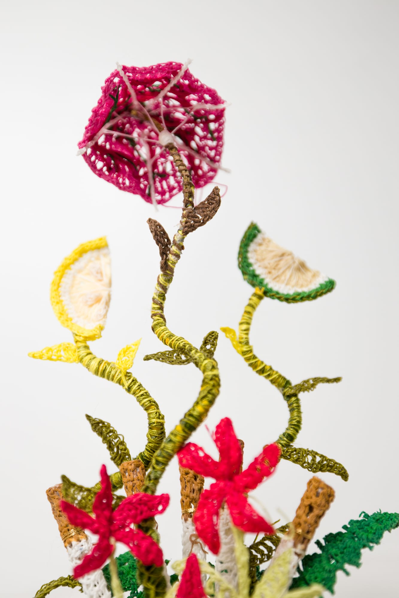 a detail of crocheted flowers and citrus slices in a freestanding sculpture