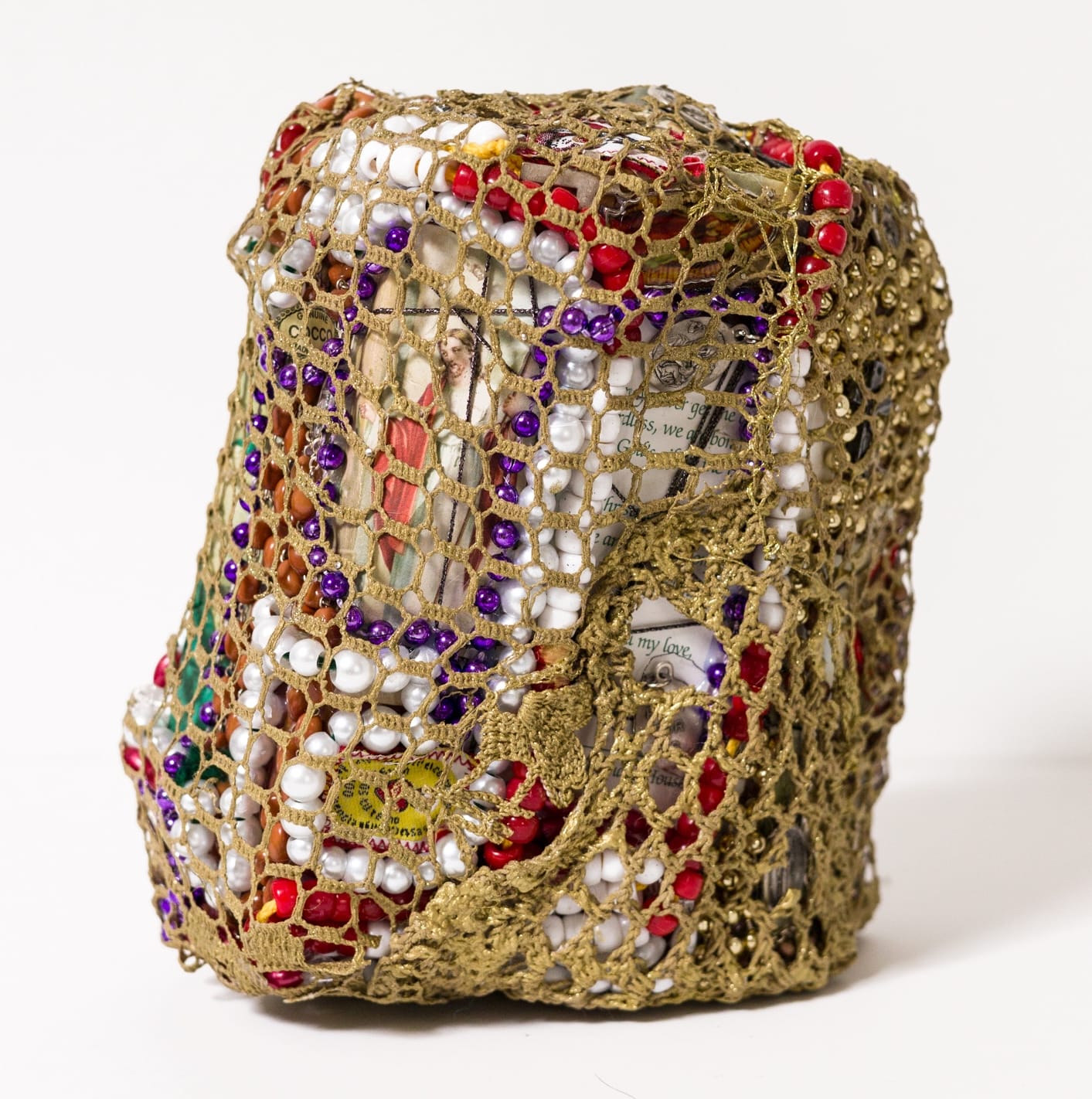 a crocheted textile sculpture with various objects inside of a netted outer sheath