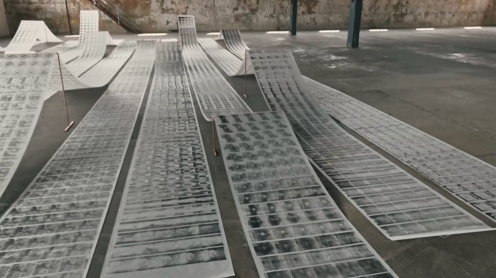 scrolls of patterned paper laying in rows on a concrete floor