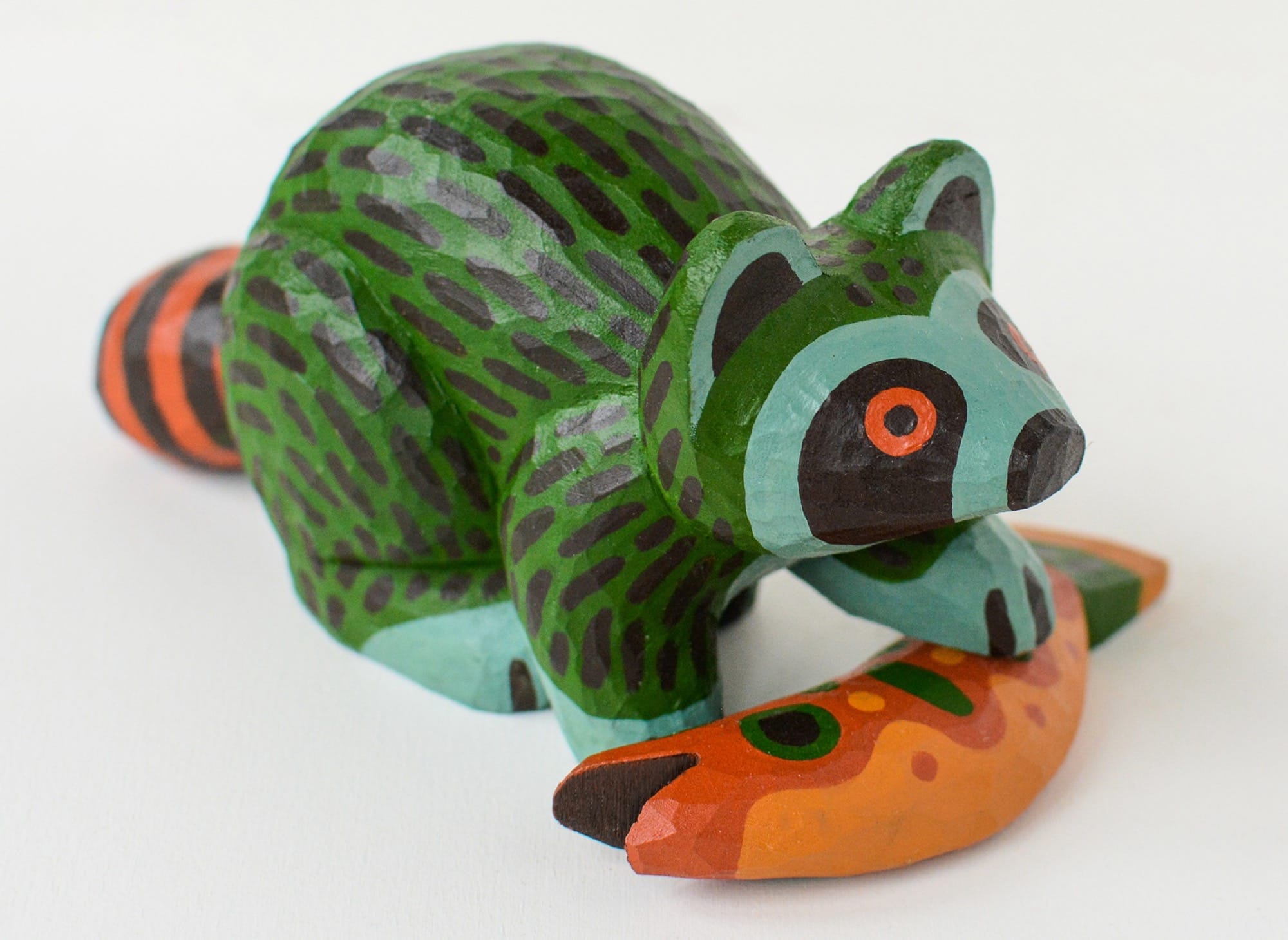 a colorful, hand-carved wooden sculpture of a raccoon with a fish