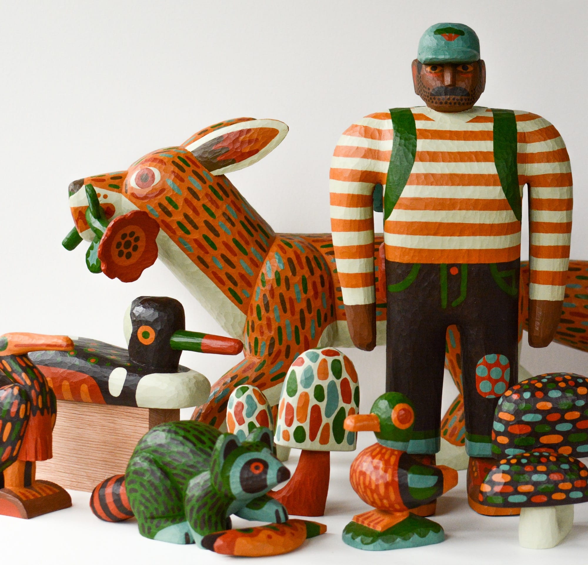 an array of colorful, hand-carved wood sculptures of forest creatures and a lumberjack in a red striped shirt