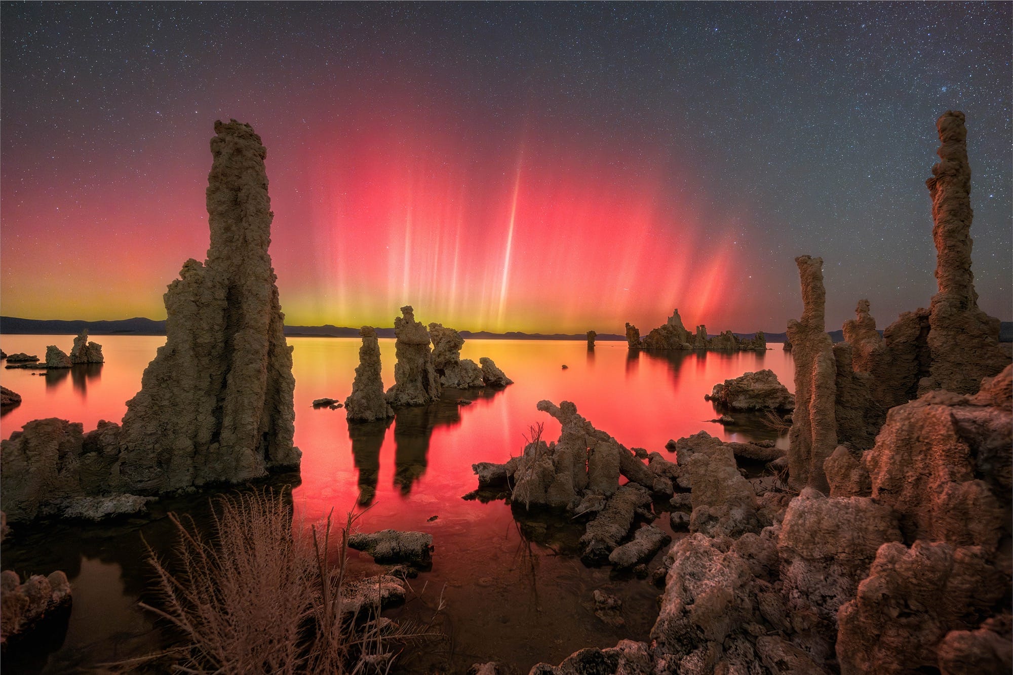 red and yellow aurora borealis in a rocky landscape